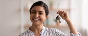 young homeowner proudly holds keys to new home - closing guarantee
